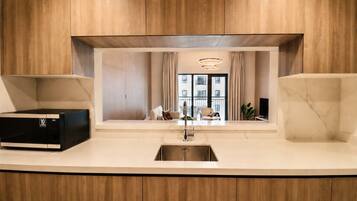 A modern kitchen with a built-in microwave, a stainless steel sink, and a view of a balcony with a dining area.
