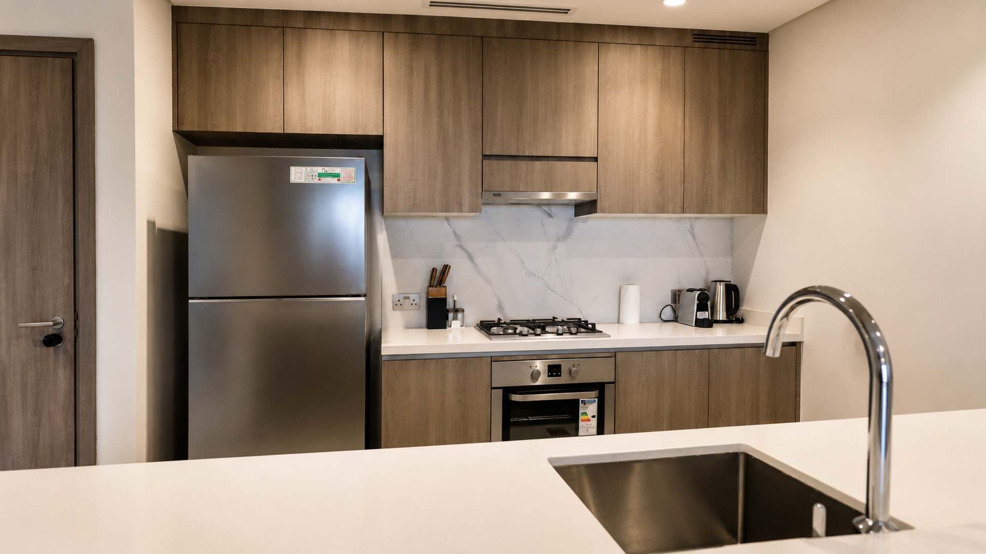 A modern kitchen with wooden cabinets, stainless steel appliances, and a marble backsplash.