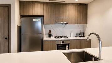 A modern kitchen with wooden cabinets, stainless steel appliances, and a marble backsplash.