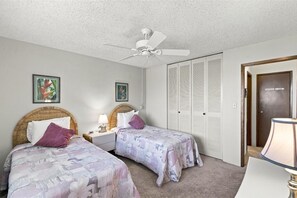 A bedroom with two beds, a ceiling fan, and a wardrobe. - Menehune Shores #321 2 Bedroom Condo (Kihei)