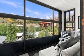 A room with large windows, a sofa, and a view of a mountainous landscape. - MP326 Mountain Plaza 2 Bedroom 3 Bath 2 Condo (Copper Mountain)