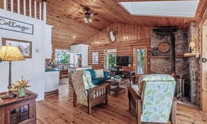 A cozy cabin interior with a wooden ceiling, a stone fireplace, and a dining area. - Lighthouse Lodge-Lion's Head, Tobermory, The Grotto, Flowerpot, Bruce Trail (Lion's Head)