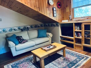 A cozy living room with a striped sofa, a wooden coffee table, and a bookshelf. - Lighthouse Lodge-Lion's Head, Tobermory, The Grotto, Flowerpot, Bruce Trail (Lion's Head)