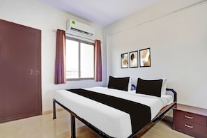 A bedroom with a bed, a wardrobe, an air conditioning unit, a window with curtains, and wall art. - Hotel O Rane Nagar (Nashik)