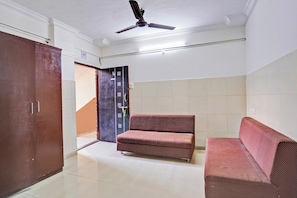 Una habitación con ventilador de techo, sofá, armario y puerta.