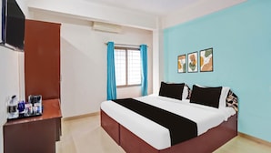 A hotel room with a bed, a TV, a desk, and a window with curtains. - Hotel O Rane Nagar (Nashik)