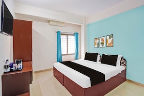 A hotel room with a bed, a TV, a desk, and a window with curtains. - Hotel O Rane Nagar (Nashik)