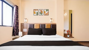 A hotel room with a large bed, a nightstand with a lamp, a wall-mounted light fixture, and a mirror. - Hotel O Main Market Mahabaleshwar (Mahabaleshwar, Pune)