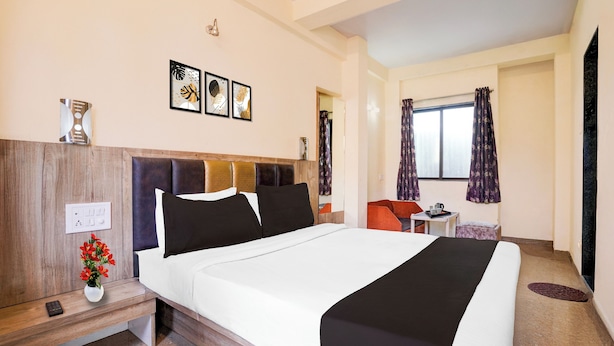 A hotel room with a bed, bedside table, and a small table with a cup and saucer. - Hotel O Main Market Mahabaleshwar (Mahabaleshwar, Pune)