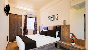 A modern hotel room with a bed, a bedside table, a mirror, and a window with curtains. - Hotel O Main Market Mahabaleshwar (Mahabaleshwar, Pune)
