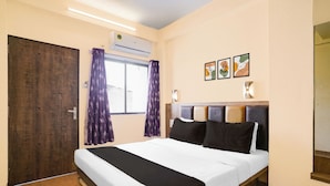 A hotel room with a bed, an air conditioning unit, a window with curtains, and wall-mounted artwork. - Hotel O Main Market Mahabaleshwar (Mahabaleshwar, Pune)