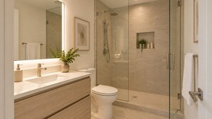 Ein modernes Badezimmer mit einer einachigen Duschkabine, einer weißen Toilette und einem Waschtisch mit Spiegel und Pflanze.