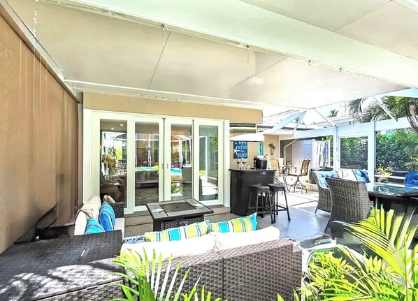An outdoor patio area with a dining table, chairs, and a bar area.