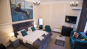 Een hotelkamer met een groot bed, een televisie, een zithoek en kunst aan de muur.