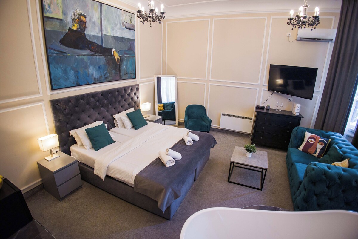 Ein Hotelzimmer mit einem großen Bett, einem Fernseher, einer Sitzecke und Bildern an der Wand.