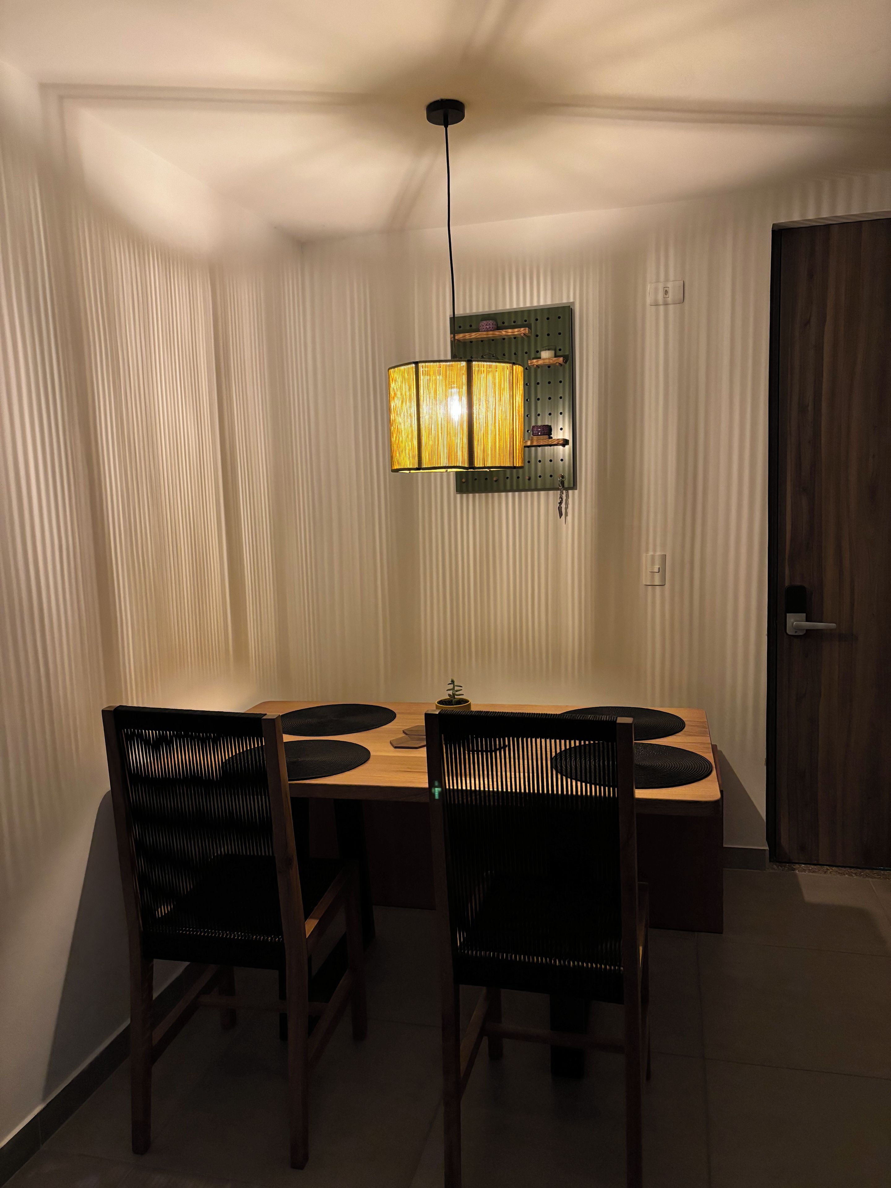 A dining area with a wooden table, four chairs, and a hanging light fixture.