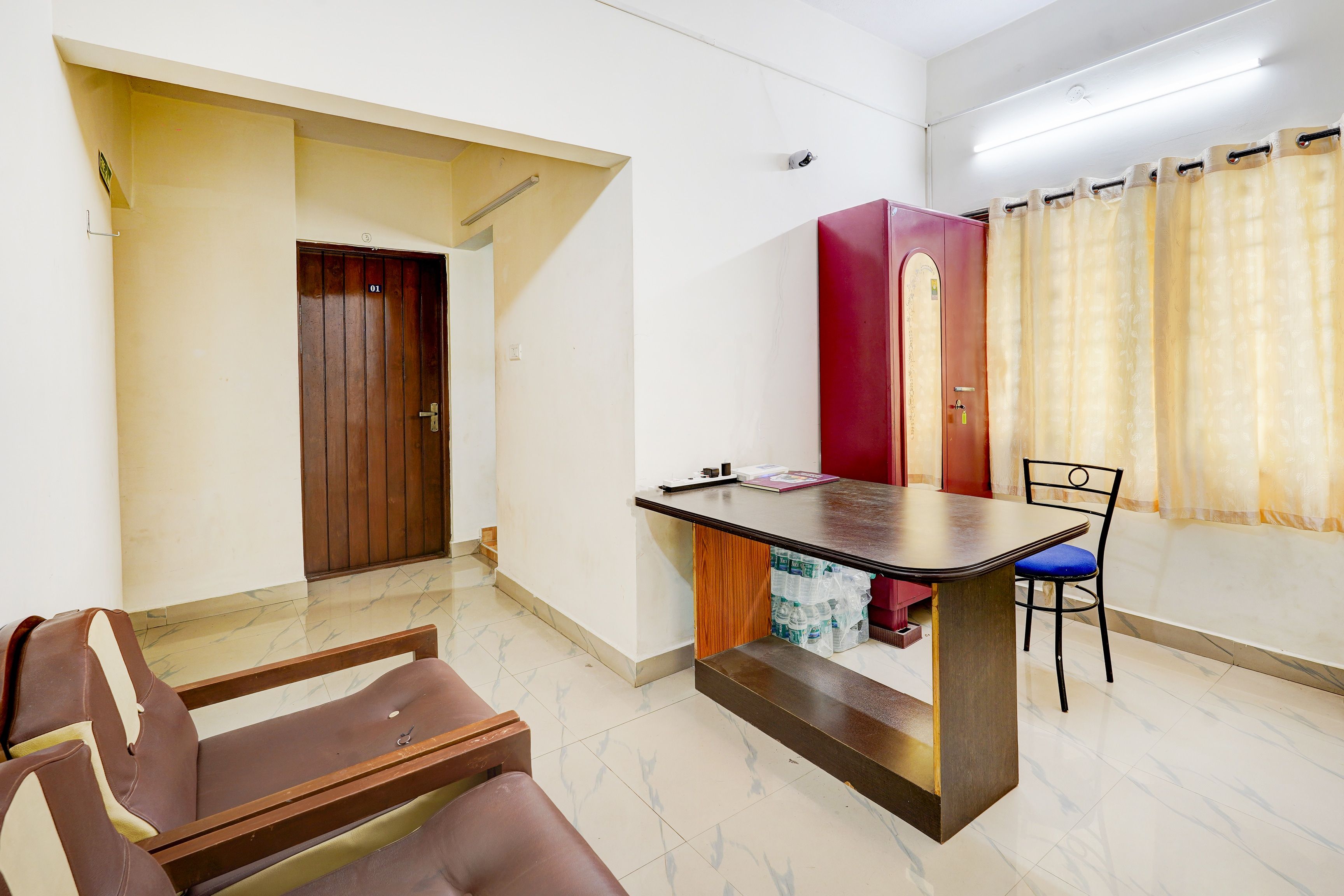 A room with a dining table, chairs, a red cabinet, and a door.