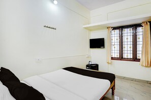A hotel room with a bed, a television, a window with curtains, and a small table with a kettle and cups. - Hotel O Kilpauk Near Don Bosco College (Chennai)