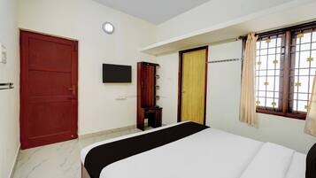 A bedroom with a bed, a wardrobe, a television, and a window with a curtain.