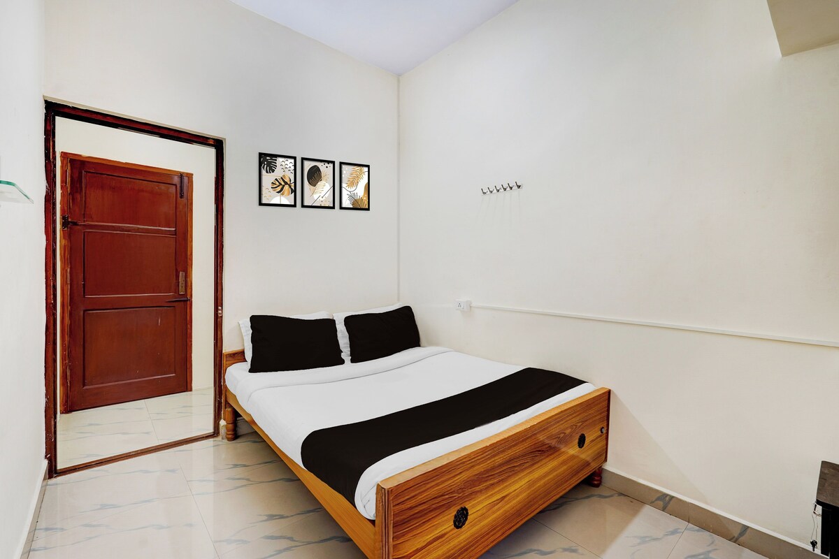 A bedroom with a wooden bed, a door, and three framed pictures on the wall.