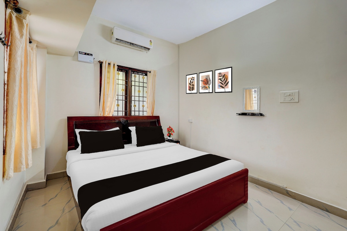 A hotel room with a bed, curtains, an air conditioning unit, a nightstand, a wall-mounted mirror, and framed artwork.
