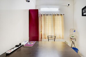 A small room with a table, a chair, a water dispenser, and a curtain.