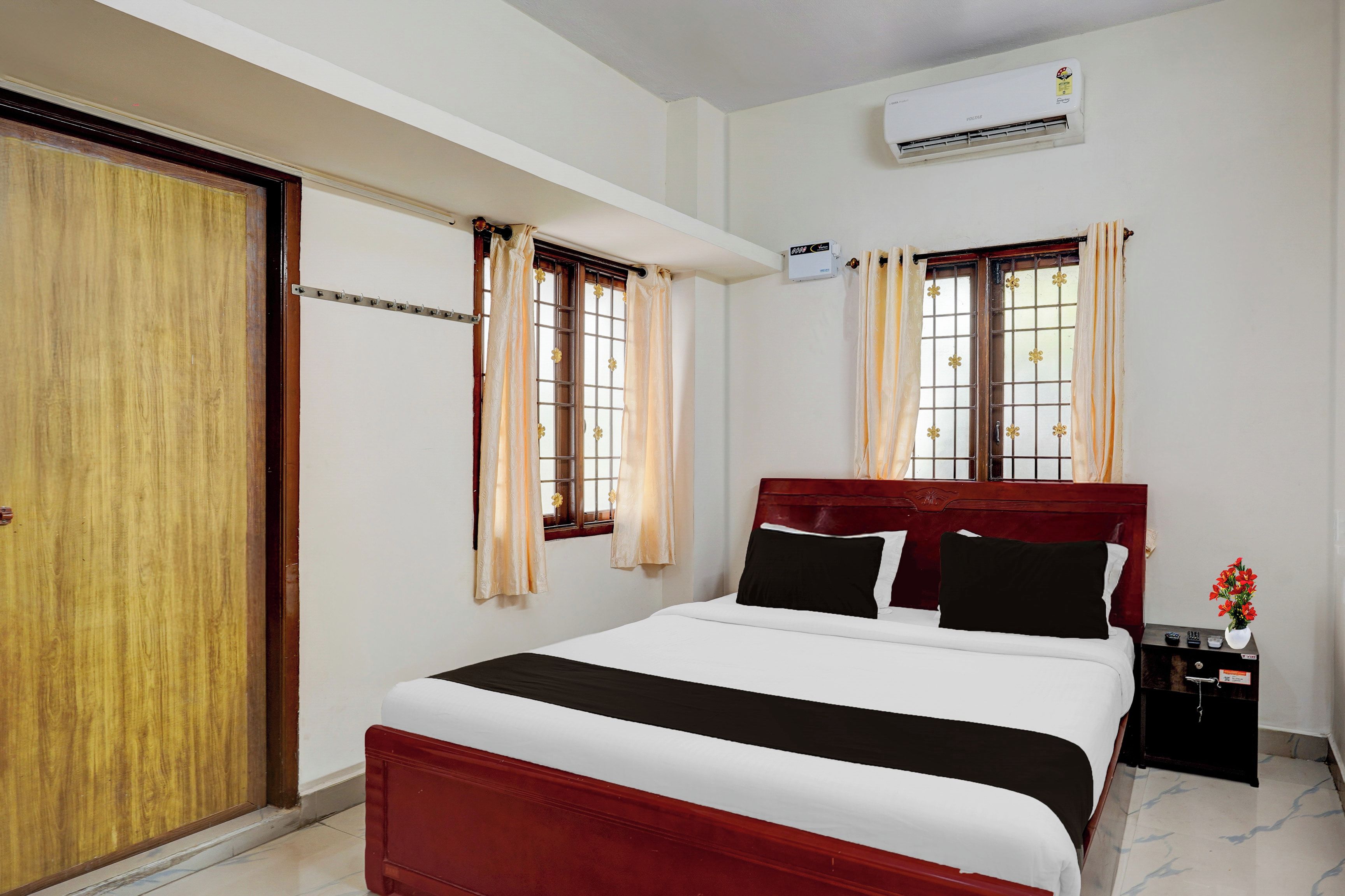 A hotel room with a bed, a wardrobe, a nightstand, and an air conditioning unit.