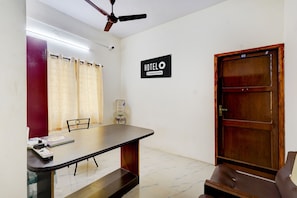 A hotel room with a bed, a desk, a chair, a water dispenser, a ceiling fan, and a door. - Hotel O Kilpauk Near Don Bosco College (Chennai)