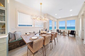 Un espace repas avec vue sur l’océan, un lustre et une table de buffet.
