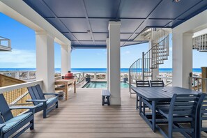 Un espace extérieur abrité avec une piscine, des sièges et une vue sur la plage.