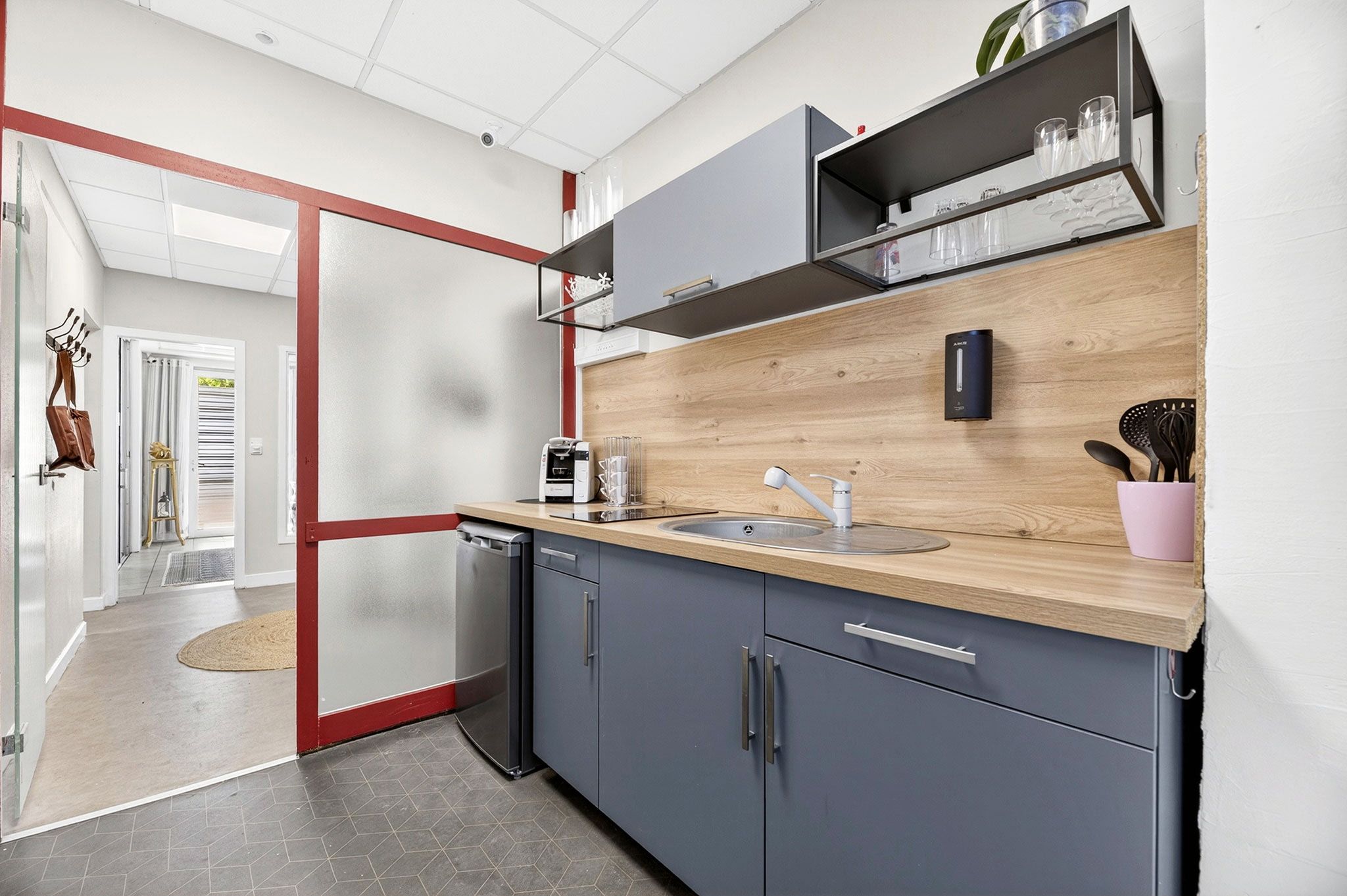 A modern kitchen with grey cabinets, a wooden countertop, a built-in sink, and a coffee machine.