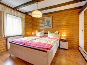 A cozy bedroom with a wooden floor, a bed with pink bedding, two bedside tables with lamps, and a window with curtains. - 14th Floor With Panoramic Balcony and Lake View (Arrach)