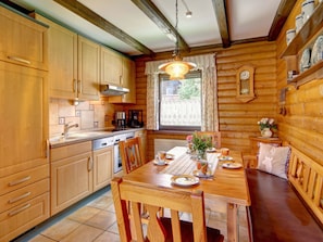A wooden cabin interior with a kitchen, dining table, and a window with curtains. - 14th Floor With Panoramic Balcony and Lake View (Arrach)