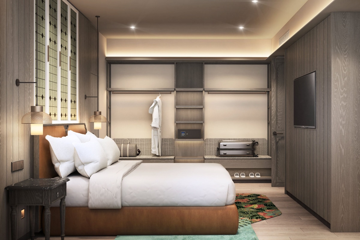 A modern hotel bedroom with a large bed, a wardrobe, a television, and a bathroom.
