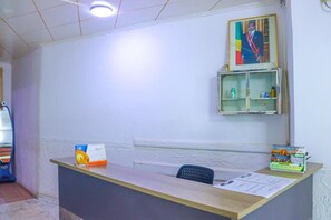 A reception desk with a calendar, a framed portrait, and a shelf with items.