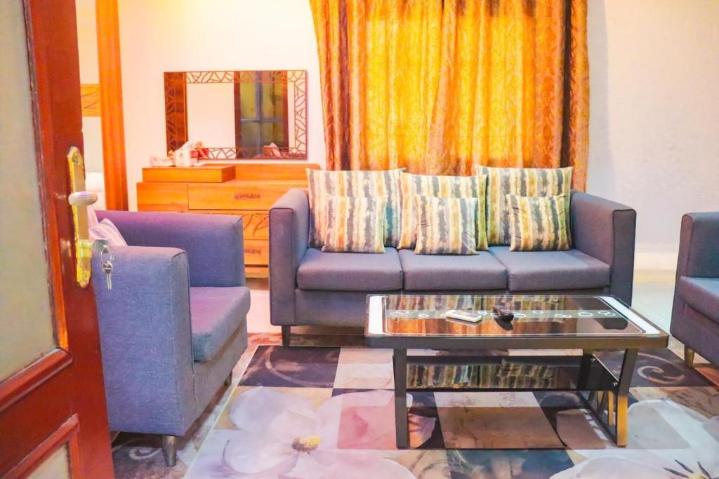 Ein Wohnzimmer mit einer Couch, Sesseln, einem Couchtisch und einem gemusterten Teppich.