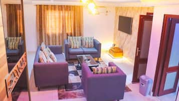 A living room with a sofa set, a coffee table, and a television mounted on the wall.
