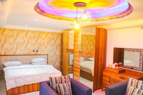 Una habitación de hotel con una cama grande, un sofá, un aparador y un espejo.