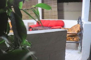 A room with a red sofa, a patterned armchair, and a potted plant in the foreground.
