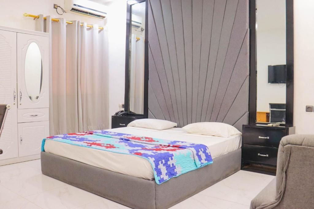 A bedroom with a bed, bedside tables, a wardrobe, and a mirror.