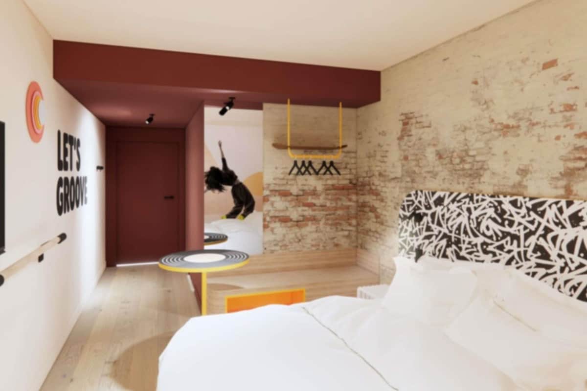 A modern bedroom with a bed, a small table, and a wall with a graffiti-style design.