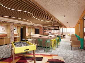 A modern bar area with a foosball table, bar stools, and a seating area with colorful chairs. - Ibis Styles Valence (ouverture Automne 2026) (Valence)