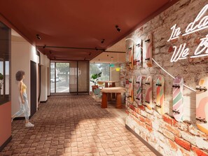 A modern interior with a brick floor, a wall with skateboards, and a neon sign. - Ibis Styles Valence (ouverture Automne 2026) (Valence)