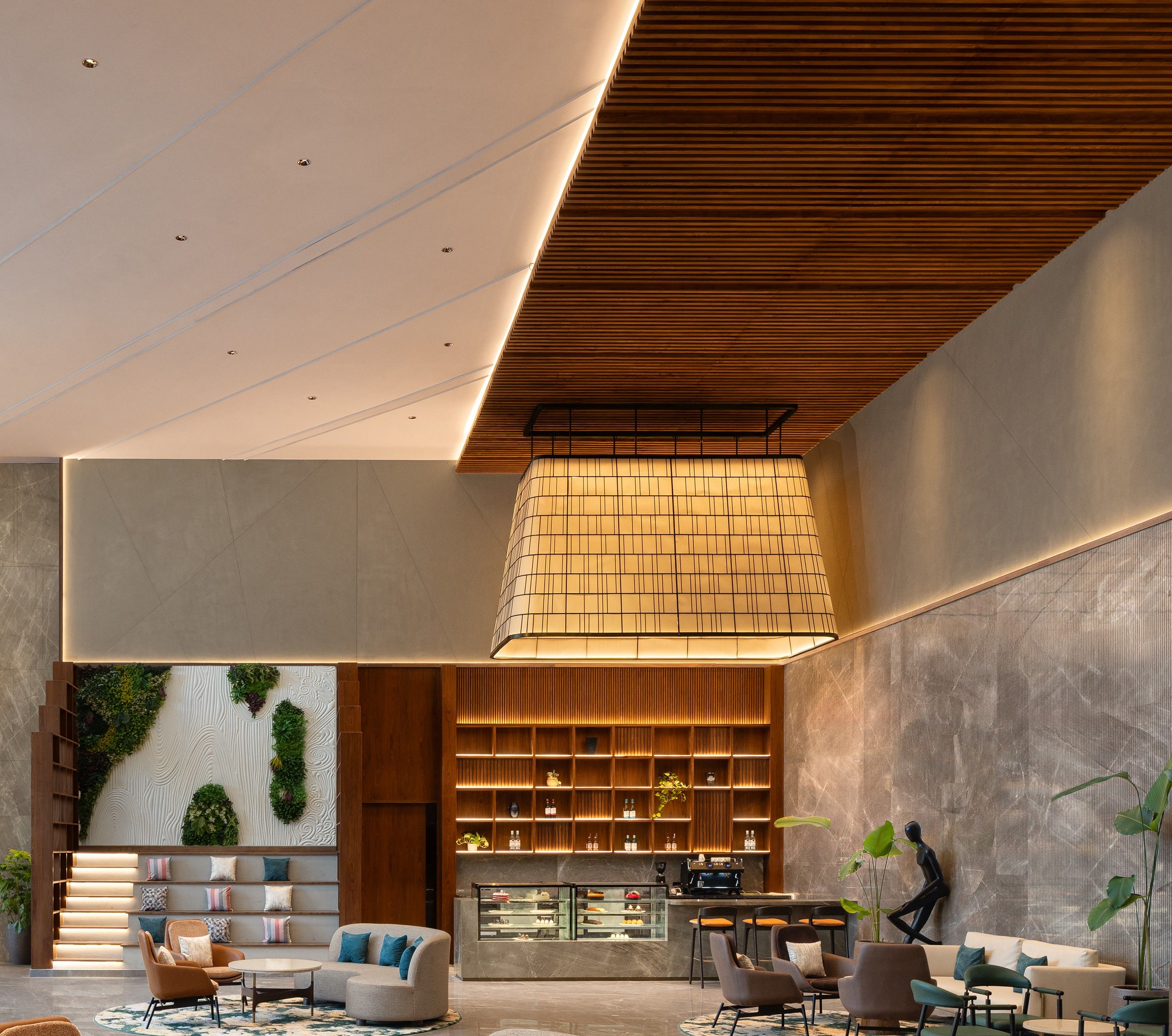 Un interior moderno con una zona de estar central, una encimera de cocina y una pared decorativa con diseño geométrico.