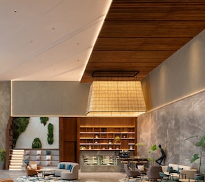 A modern interior with a central seating area, a kitchen counter, and a decorative wall with a patterned design. - Novotel Bhopal (Bhopal)