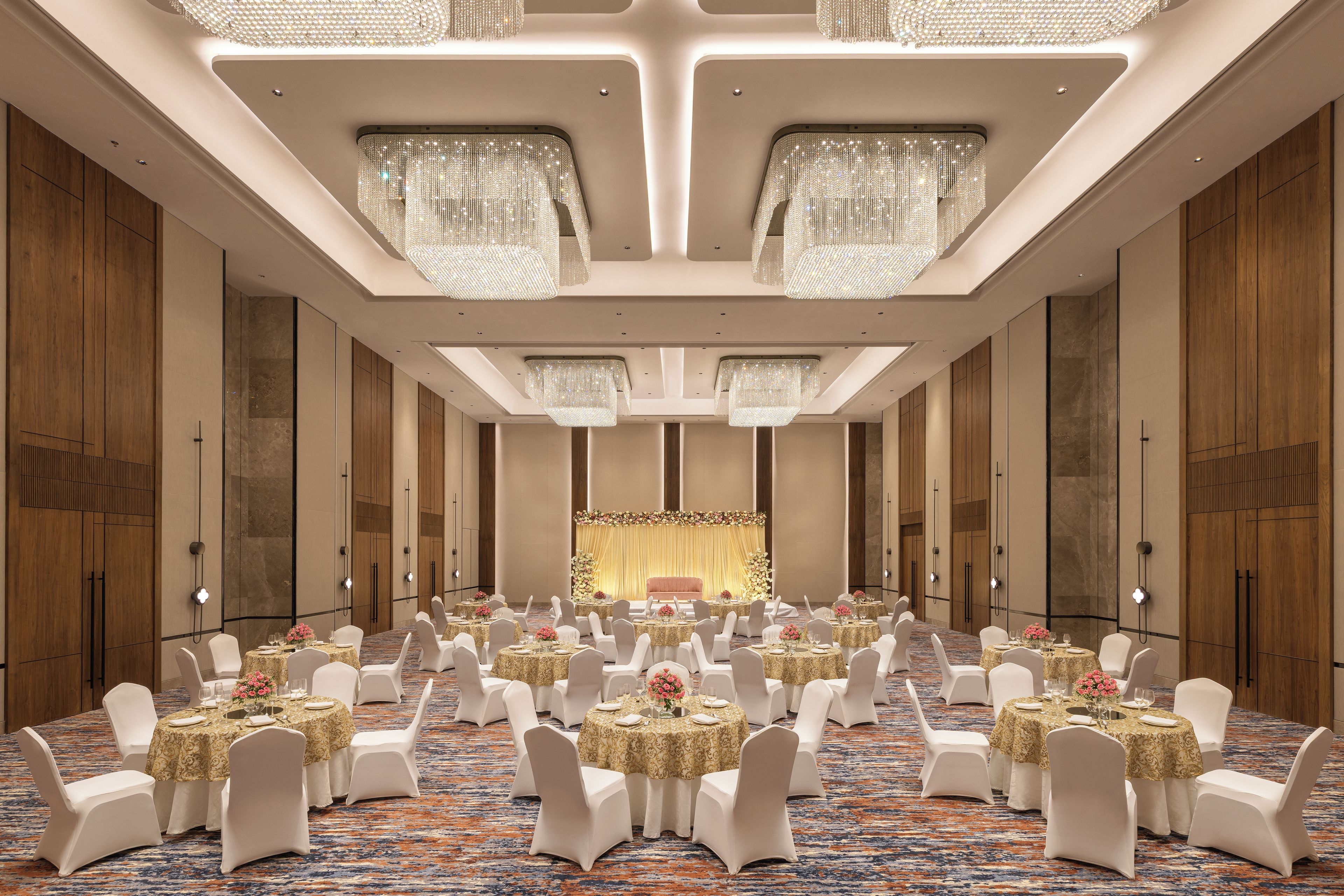 Un salón de banquetes con mesas redondas, sillas blancas y candelabros.