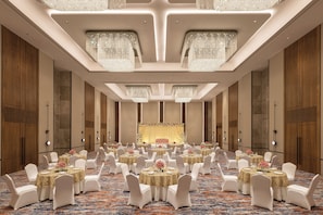 A banquet hall with round tables, white chairs, and chandeliers. - Novotel Bhopal (Bhopal)