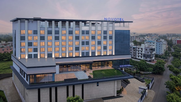Ett modernt hotell med ett platt tak, flera våningar och en tydlig skylt med texten ”NOVOTEL”.