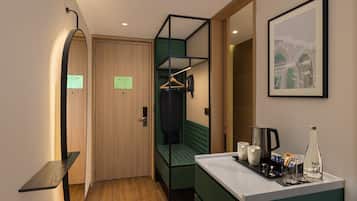 A compact hotel room with a bunk bed, a small kitchenette, a seating area, and a framed artwork on the wall.