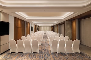 A hotel conference room with rows of white chairs, a patterned carpet, and a modern ceiling design. - Novotel Bhopal (Bhopal)